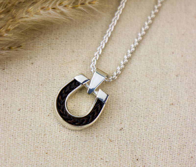Silver necklace with a unique pendant on a textured beige fabric background