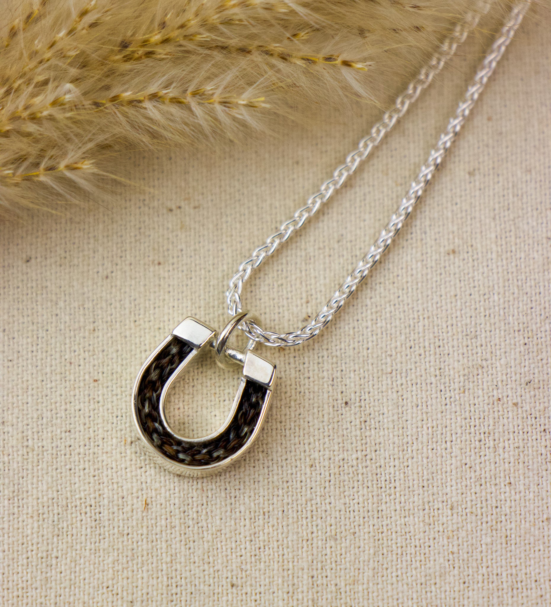 Silver necklace with a unique pendant on a textured beige surface