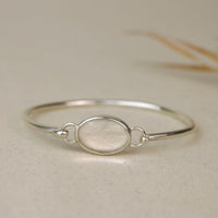 Silver bracelet with a central oval set with dog fur on a beige background