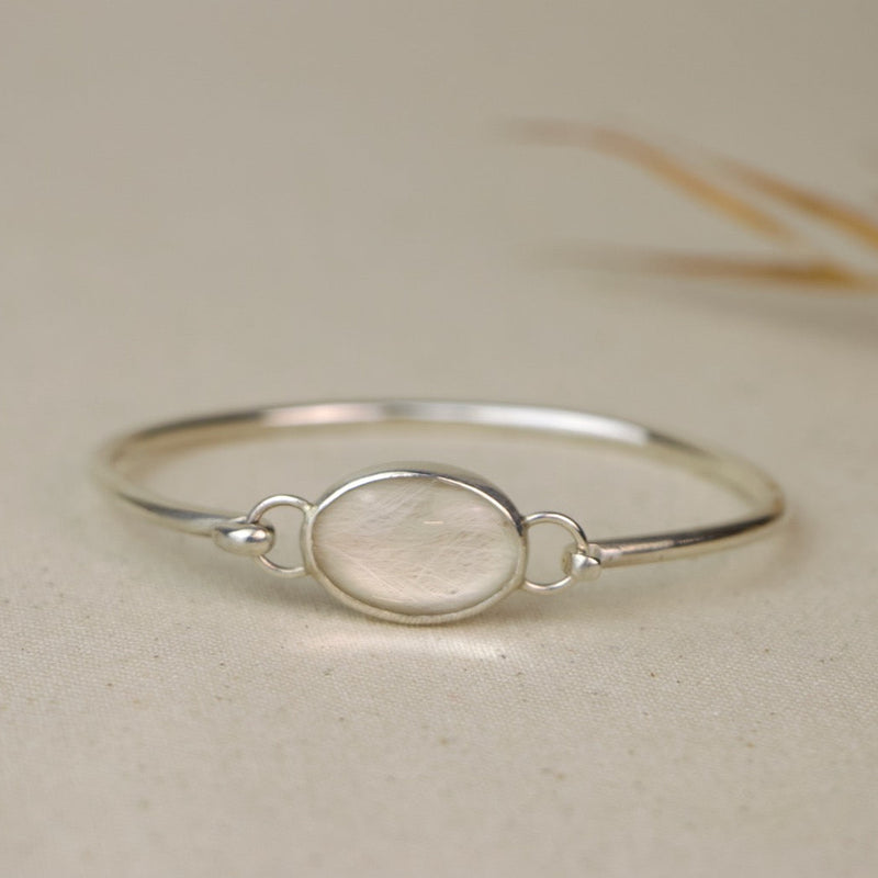 Silver bracelet with a central oval set with dog fur on a beige background